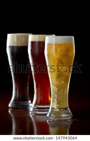 dark, red and light beer served on a dark bar