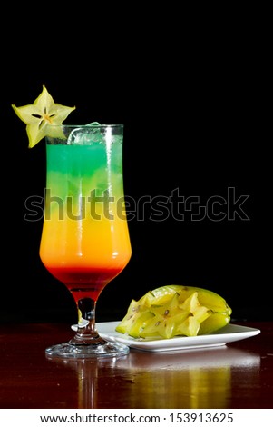 tropical drink served on a wooden bar garnished with a carambola slice on the rim