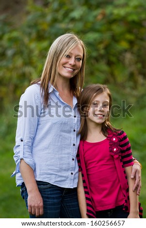 happy mother and daughter posing outdoors with a natural green background