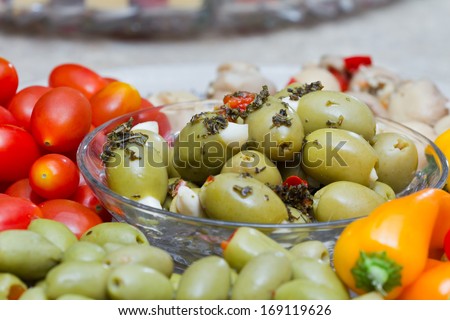 close up of a platter with different olives and vegetables with oil and seasoning