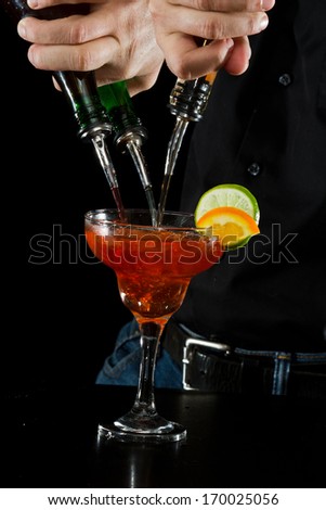 action shot of a bartender pouring red margarita using multiple bottles