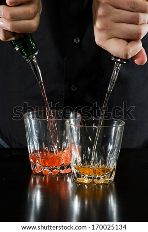 action shot of a bartender pouring two cocktails at the same time
