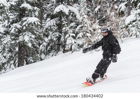 adult male snowboarding in the mountains of northern Idaho in snowy winter conditions