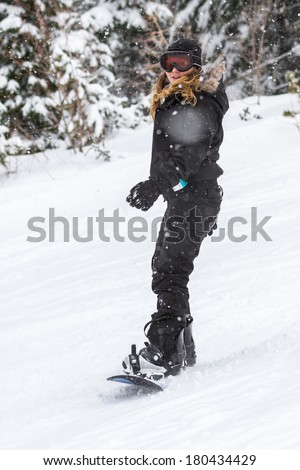 beautiful young woman snowboarding on the slopes of northern Idaho in snowy winter conditions