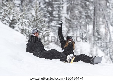 young couple with snowboards sitting on fresh snow in the mountains of northern Idaho