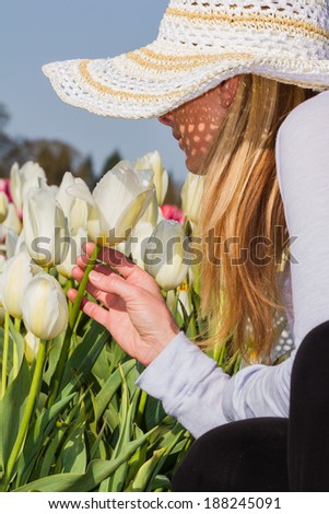 beautiful caucasian woman smelling the tulips in the field