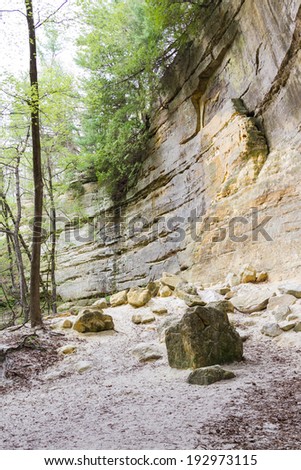 large sandstone cliffs with rocks that have fallen in the past turning into powder on the ground, St Louis State Park Illinois