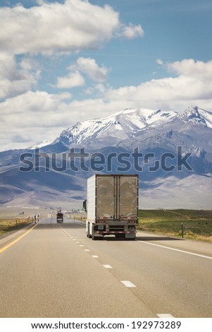 shipping truck on a highway in nevada with spring snow on large tall mountains in the background