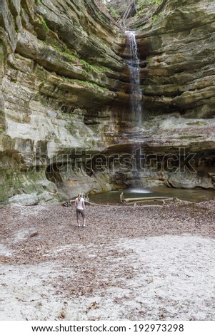 woman watching the waterfall at the end of the St. Louis Canyon waterfall in Starved Rock State Park in Illinois