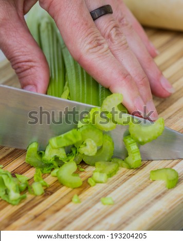 cutting fresh celery into small slices on a wooden cutting board
