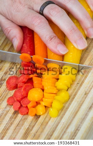 close-up in action of a cook slicing raw carrots arranged for a colorful effect