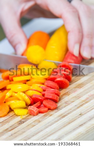 close-up in action of a cook slicing raw carrots arranged for a colorful effect