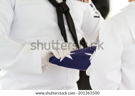 active navy representatives folding a flag as part of a ceremony for a veterans funeral
