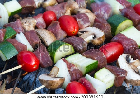 close up of meat and vegetable skewers on a smokey grill for a hickory taste