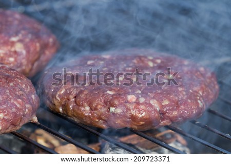 close up of hand formed hamburger patties on an outdoor grill with hickory wood chips for a smoky flavor