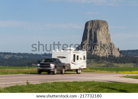 Roadside view of Devils Tower National Monument with a slow shutter sped to blur the moving vehicle in the foreground