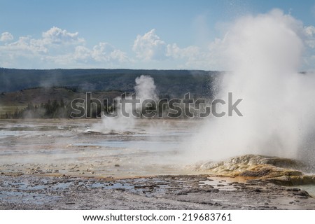 closeup of a geyser in yellowstone with hot water and steam flowing out of it