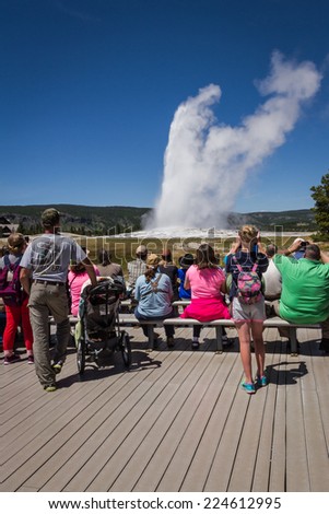 Yellowstone national park, Wyoming - July 22 : group of tourists standing watching old faithful geyser; July 22 2014 in Yellowstone national park, Wyoming