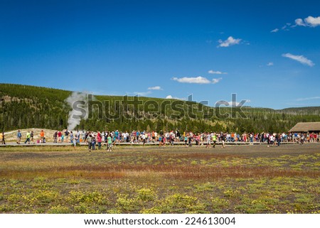Yellowstone national park, Wyoming - July 22 : group of tourists standing watching old faithful geyser; July 22 2014 in Yellowstone national park, Wyoming