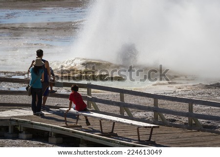 Yellowstone national park, Wyoming - July 10 : young family standing in front of an active geyser; July 010 2014 in Yellowstone national park, Wyoming
