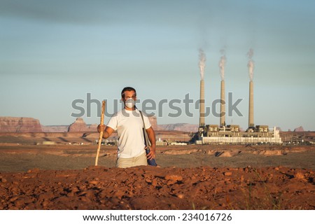 concept image of a man wearing a mask and a walking stick walking away from a coal burning power plant with dirty smoke in the air