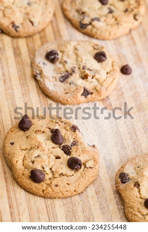 close up of a home made chocolate chip cookie on a wooden cutting board