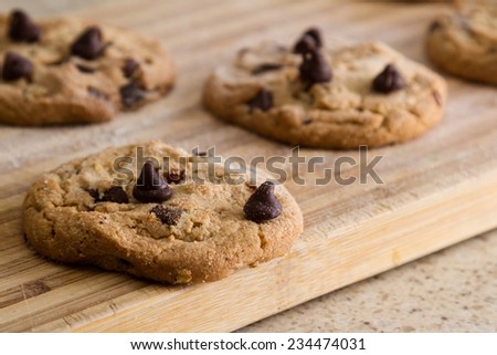close up of a home made chocolate chip cookie on a wooden cutting board