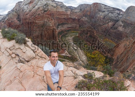 young caucasian man taking a selfie over the steep cliffs of the  Angels Landing hiking trail in Zion NP