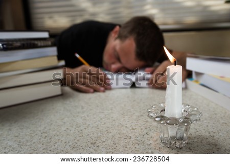 over worked researcher sleeping on an open book with many more on the table