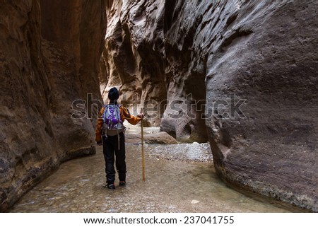 man hiking the Narrows in Zion National park with the virgin river flowing through the slot canyon