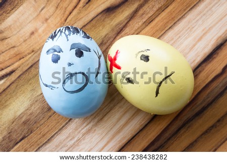 hand painted easter eggs with sad and scarred expressions on a wooden table