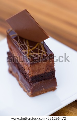 close up of a cake with multiples layers of chocolate and caramel garnished with a dark chocolate square