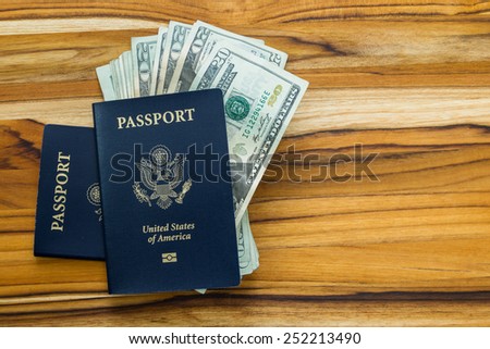 close up of two american passports and cash money on a wooden table for a travel concept