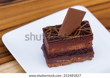 close up of a cake with multiples layers of chocolate and caramel garnished with a dark chocolate square