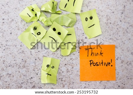 concept for a positive attitude with small crumbled up sad faces and a note with the phrase think positive