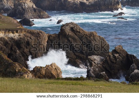 dramatic landscape of the California coast with waves splashing on the cliffs and rocks