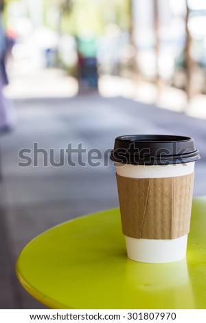 paper cup with a lid holding a hot beverage on a side walk table