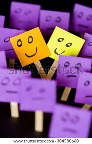 Concept for being different and being happy in a word of normal, hand drawn faces on sticky notes over a black background