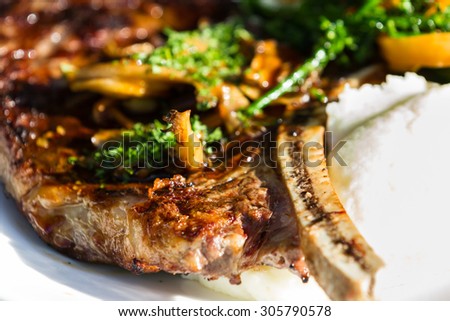 close up of a bone in ribeye served with broccolini and mashed potatoes