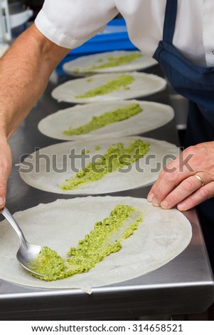 executive chef spreading pesto on thin round shells for dinner service
