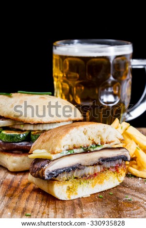 vegetarian sandwich with grilled mushroom, zucchini and onions served with fries and a cold beer
