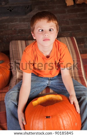 young cross eyed boy carving pumpkins for halloween