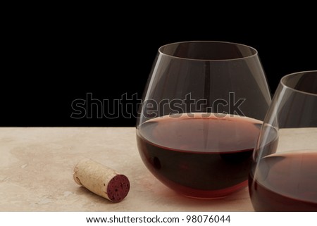 two stemless glasses of red wine served on a bar top isolated on black