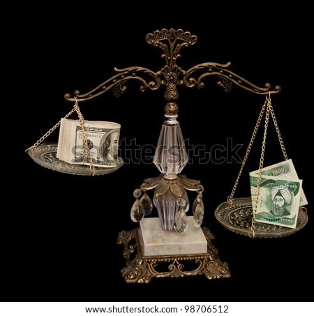 ten thousand Iraqi dinar bill and a bunch of hundred dollar bills balancing on a scale isolated on a black background