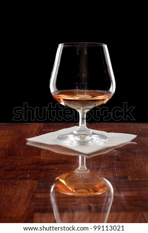 Brandy snifter on a bar top isolated on a black background