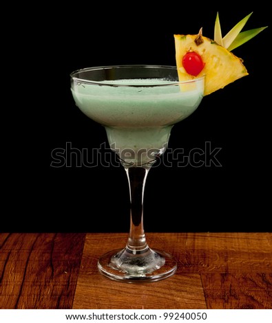 blue hawaiian cocktail isolated on a black background served on a bar top