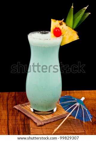blue hawaiian cocktail isolated on a black background served on a bar top