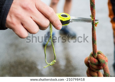 Hand with knife cutting the rope