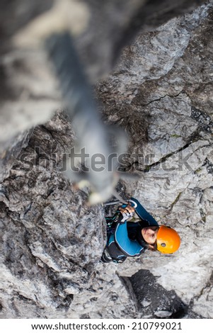 Young woman climbing on a steep rock face