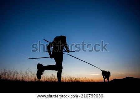 Silhouettes of a runner and a his dog during a sunrise